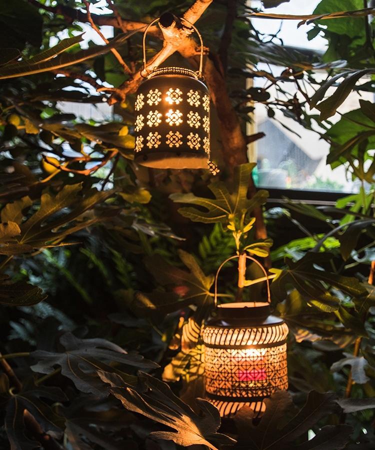 Metal lantern candle holder pair by RusticReach with floral and geometric cutouts on greenery on Tampa Home & Garden Store