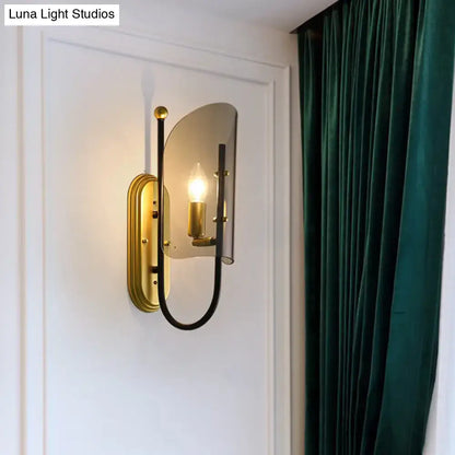 Brass smoke-glass wall lamp with black curved arm, gold backplate, single bulb on Tampa Home & Garden Store