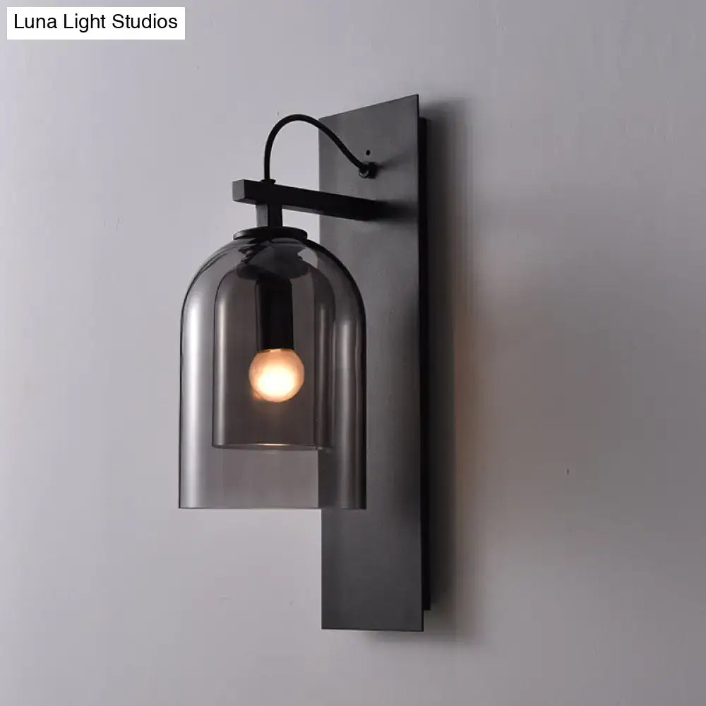 Black smoked glass sconce with a curved glass shade and exposed bulb on a matte black backplate on Tampa Home & Garden Store