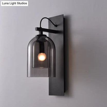 Black smoked glass sconce with a curved glass shade and exposed bulb on a matte black backplate on Tampa Home & Garden Store
