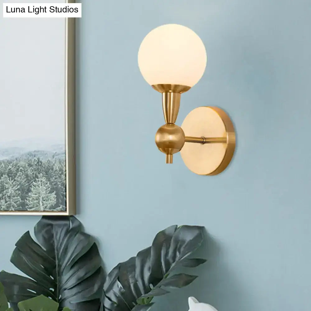 Brass opal glass orb wall sconce by Decorbites with frosted globe and gold finish on blue wall on Tampa Home & Garden Store