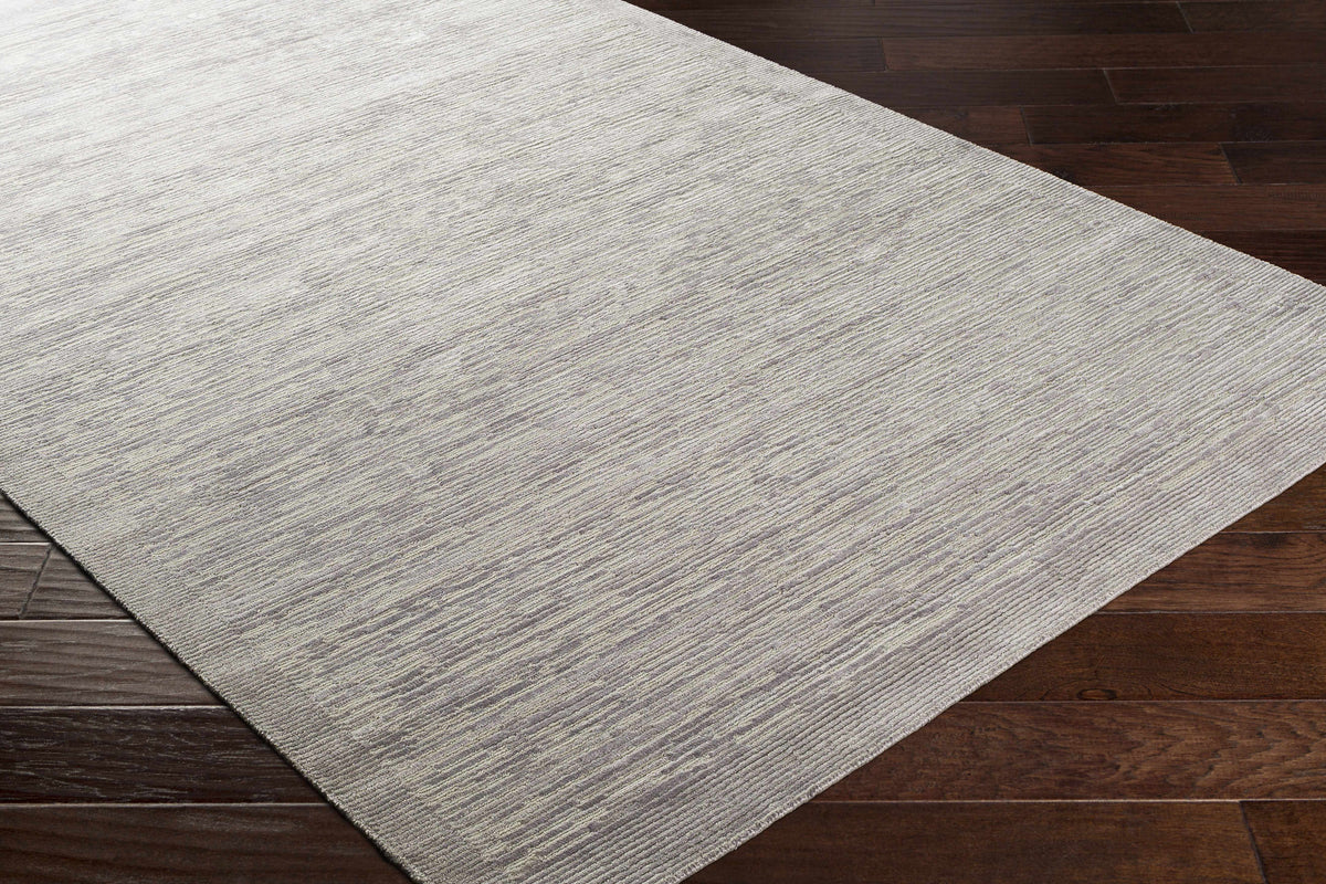 Mardi Silver Premium Wool & Silk Area Rug by Boutique Rugs with light silver-gray texture on dark wood floor on Tampa Home & Garden Store