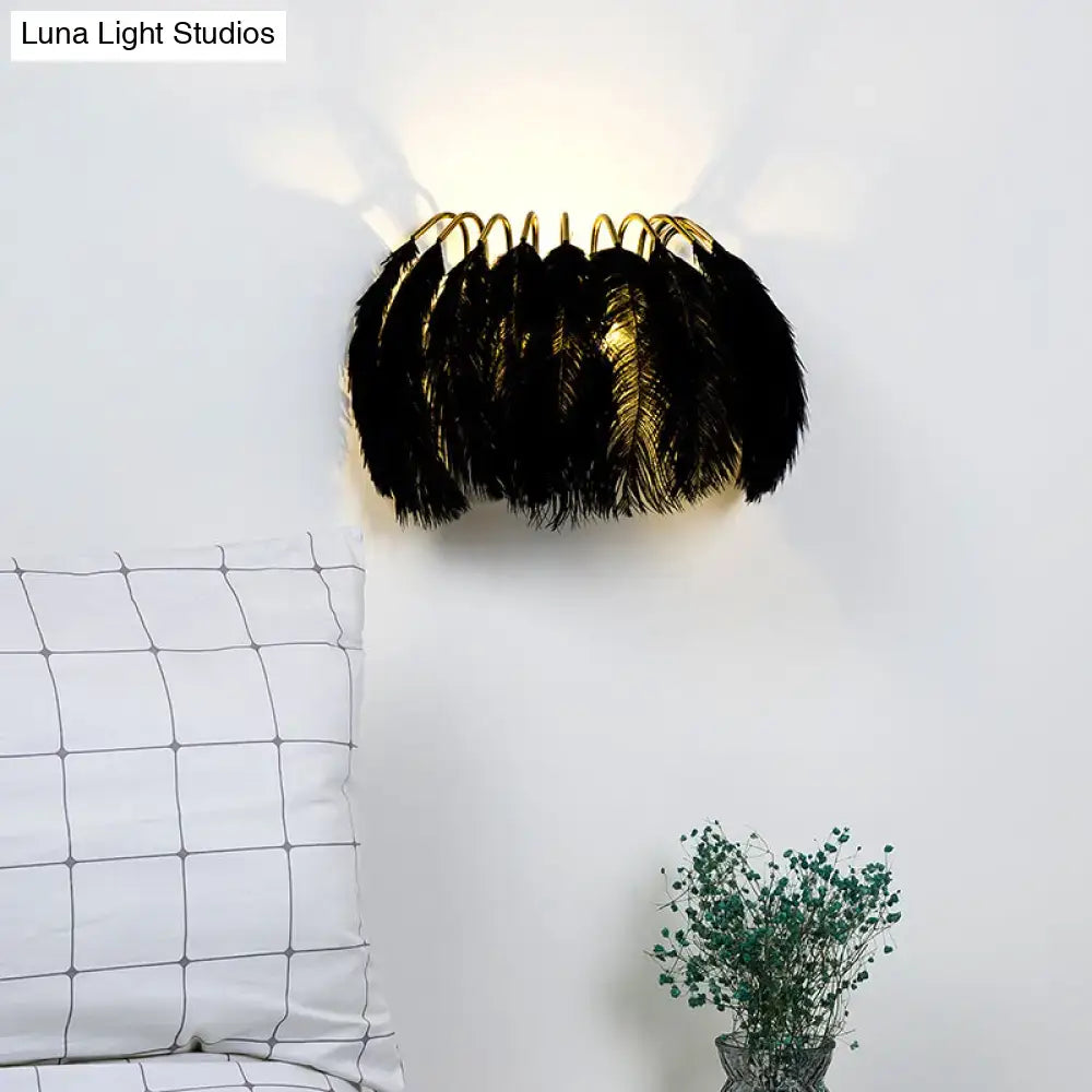 Black Gold Feather Sconce with gold arched frame wrapped in black feathers against a white wall on Tampa Home & Garden Store