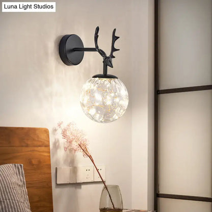 Black antler glass sconce by Decorbites; cracked-glass globe with warm light on round backplate on Tampa Home & Garden Store