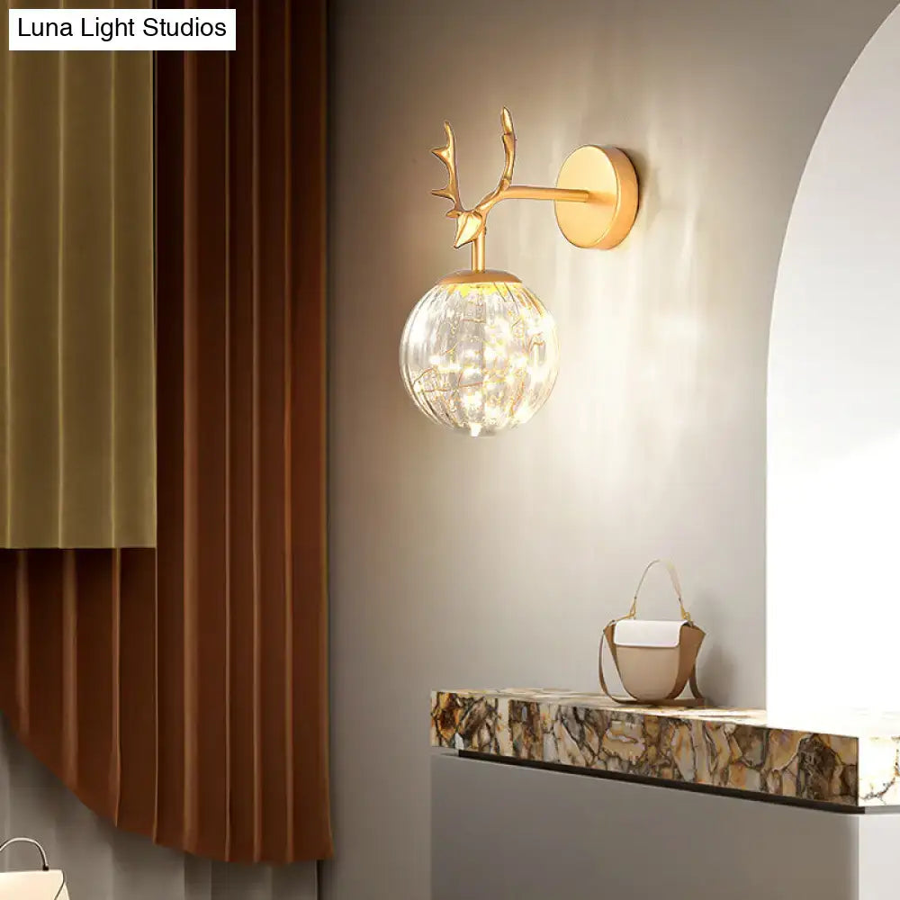 Black Antler Glass Sconce by Decorbites with gold-tone antler arm and glass orb on wall on Tampa Home & Garden Store