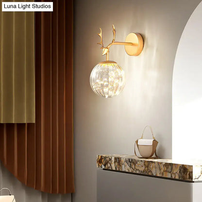 Black Antler Glass Sconce by Decorbites with gold-tone antler arm and glass orb on wall on Tampa Home & Garden Store