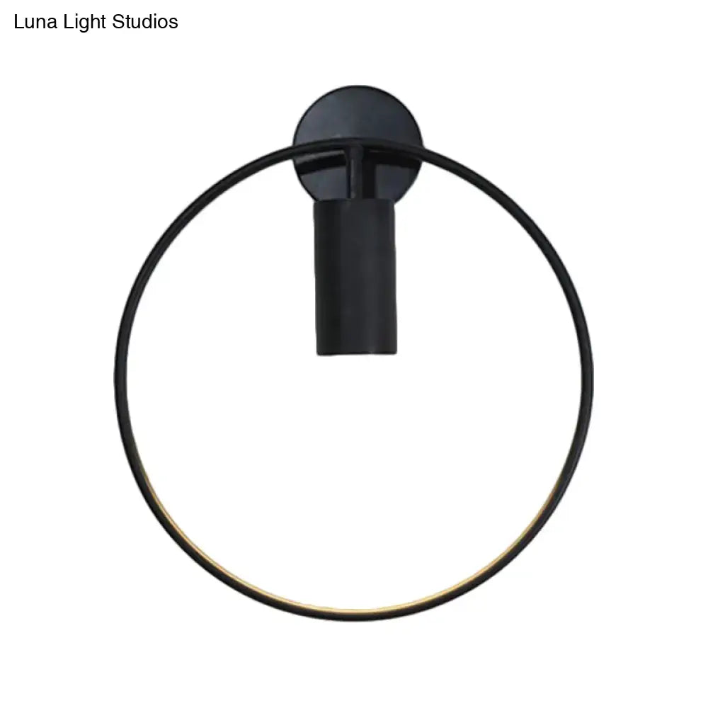 Black circular metal wall sconce with a large ring frame and a cylindrical mount on Tampa Home & Garden Store