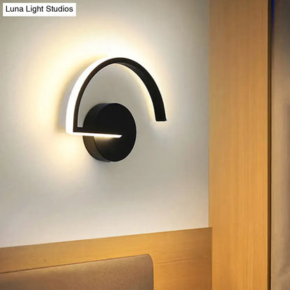 Black curved open-frame wall sconce with circular base and arching arm by Decorbites, emits soft ambient LED glow on Tampa Home & Garden Store