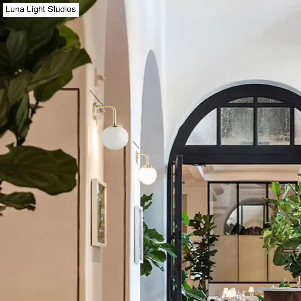 Milky Glass Ball Wall Lamp by Decorbites, brass arm wall-mounted in a bright lobby hallway on Tampa Home & Garden Store