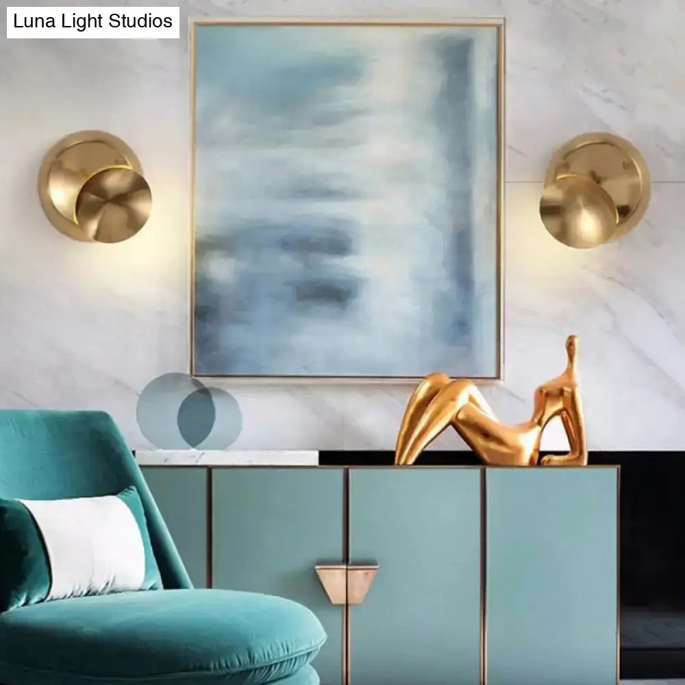 Moon-shaped wall sconces in gold finish flank a blue abstract painting above a teal cabinet on Tampa Home & Garden Store