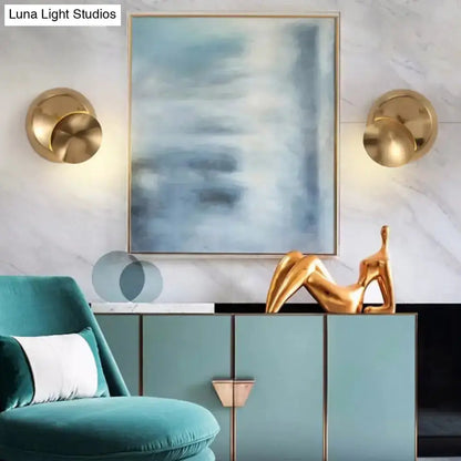 Moon-shaped wall sconces in gold finish flank a blue abstract painting above a teal cabinet on Tampa Home & Garden Store