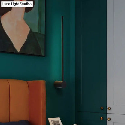 Black Needle Wall Light, slim metal rod sconce on teal wall with round mount on Tampa Home & Garden Store