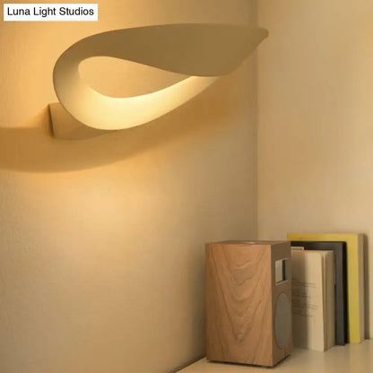 Black oval aluminum LED wall sconce with looping curved shade warm ambient glow on Tampa Home & Garden Store