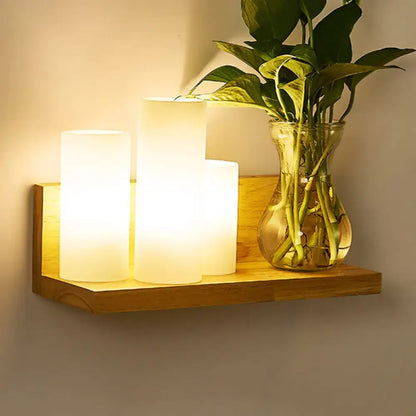 Wood Geometric Wall Sconce with warm frosted lamps on a wooden shelf beside a plant vase on Tampa Home & Garden Store