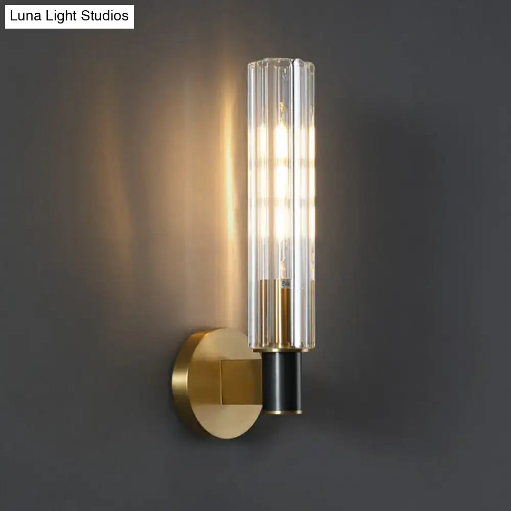 Brass tubular wall sconce with clear glass cylinder shade on round gold wall plate on Tampa Home & Garden Store