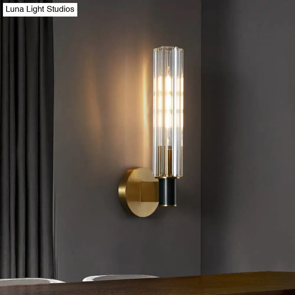 Brass tubular wall sconce with clear glass shade by Decorbites and warm glow on Tampa Home & Garden Store