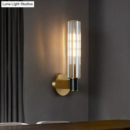 Brass tubular wall sconce with clear glass shade by Decorbites and warm glow on Tampa Home & Garden Store