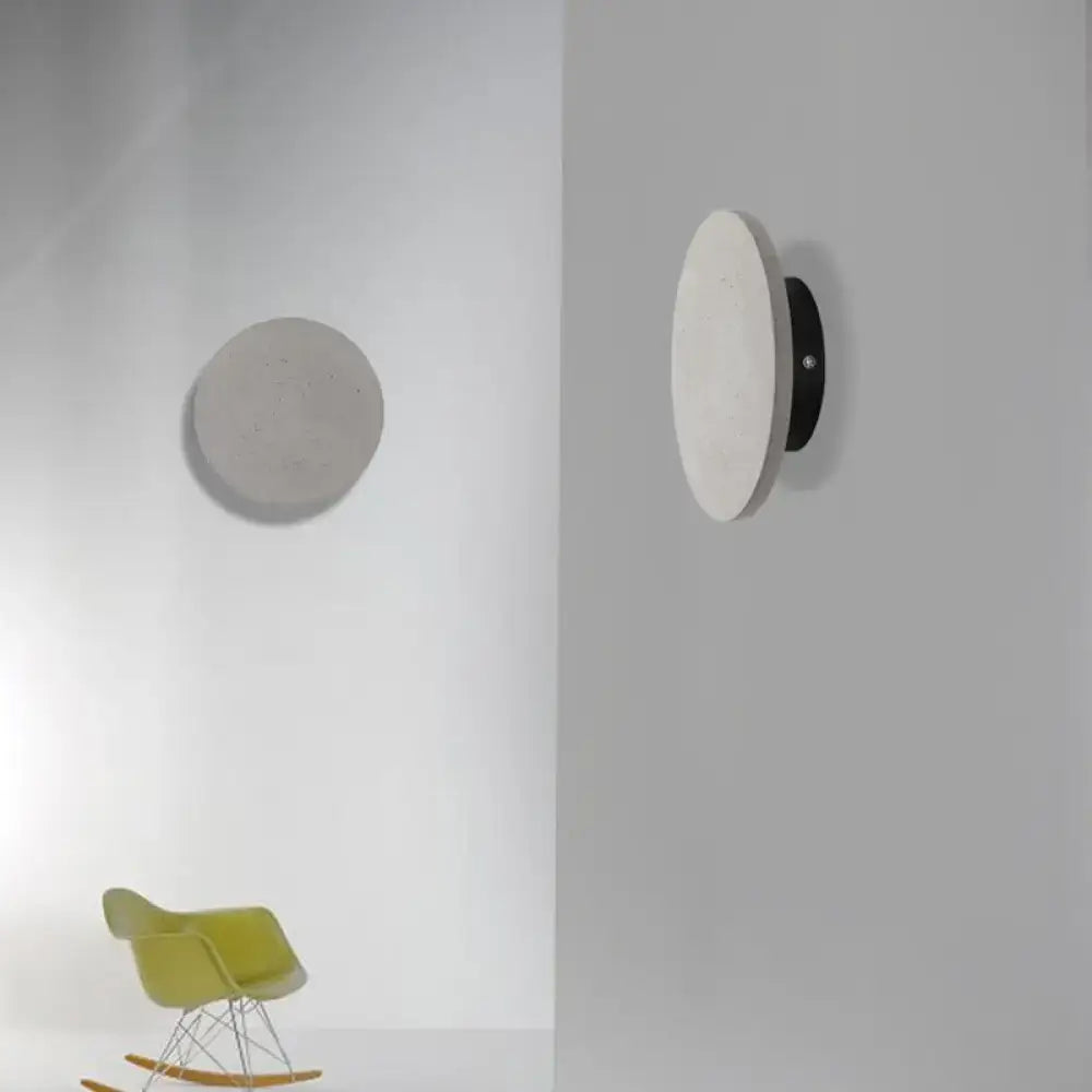 Grey cement wall sconce with round disc design and black mount on a neutral wall on Tampa Home & Garden Store