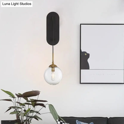 Decorbites black glass wall sconce with brass hardware and clear glass globe on Tampa Home & Garden Store