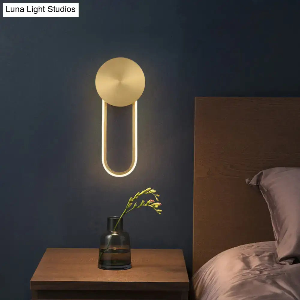 Gold elliptical wall sconce by Decorbites mounted on dark blue wall on Tampa Home & Garden Store