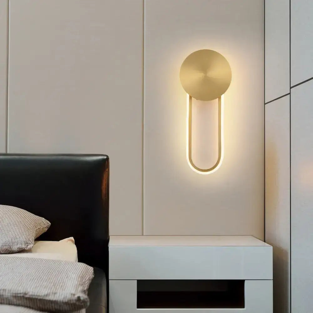 Gold elliptical wall sconce by Decorbites; metal wall light with circular backplate and U glow on Tampa Home & Garden Store