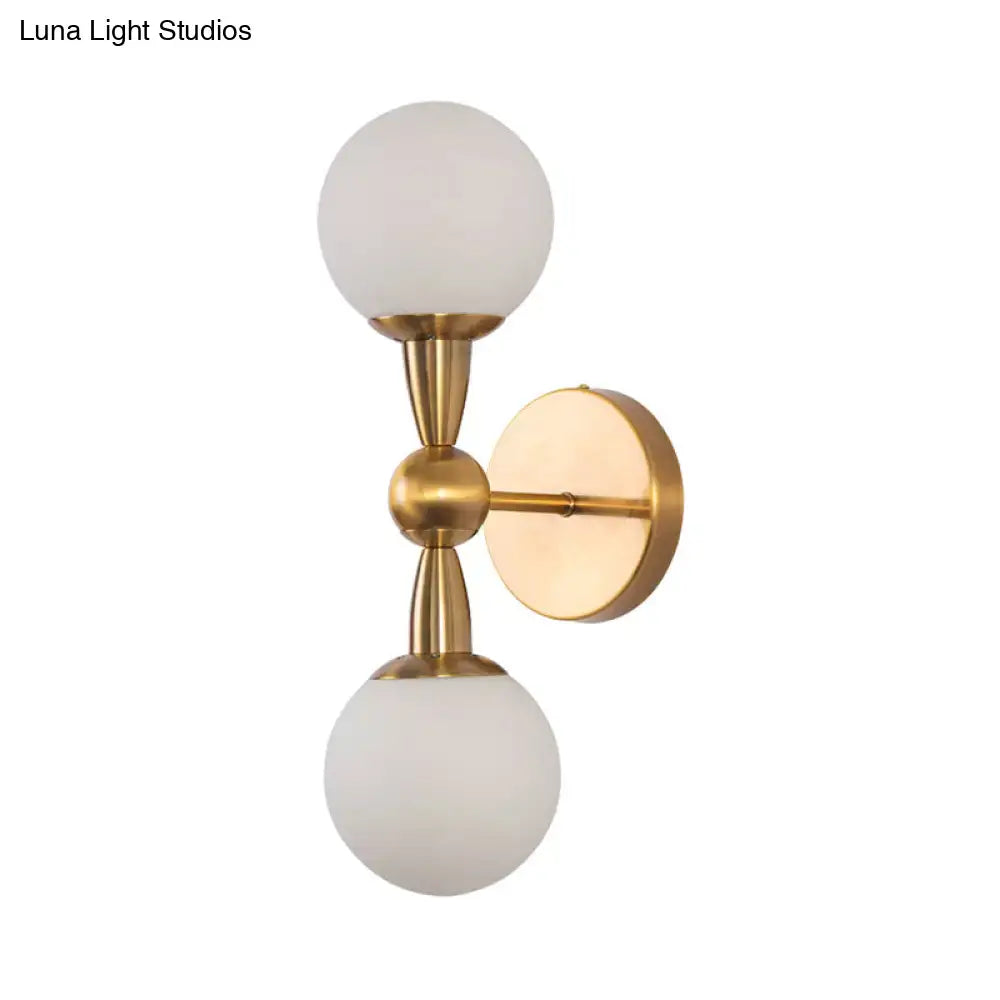 Gold hand blown sconce by Decorbites with twin frosted glass globes and brass hardware on wall on Tampa Home & Garden Store