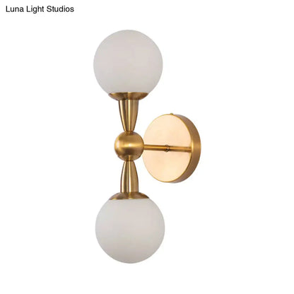 Gold hand blown sconce by Decorbites with twin frosted glass globes and brass hardware on wall on Tampa Home & Garden Store