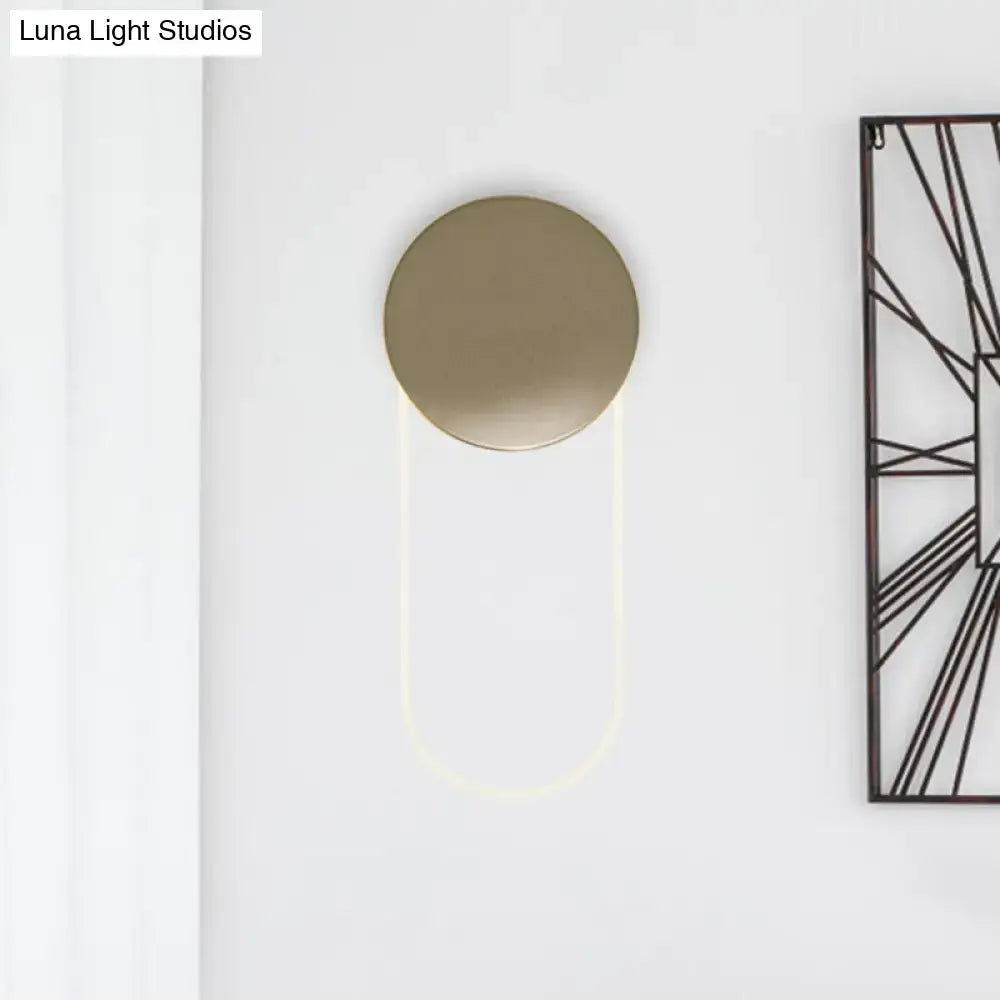 Gold oval LED wall lamp by Decorbites on white wall with round backplate and glowing U-arc on Tampa Home & Garden Store