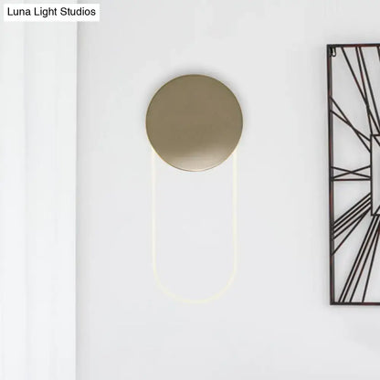 Gold oval LED wall lamp by Decorbites on white wall with round backplate and glowing U-arc on Tampa Home & Garden Store