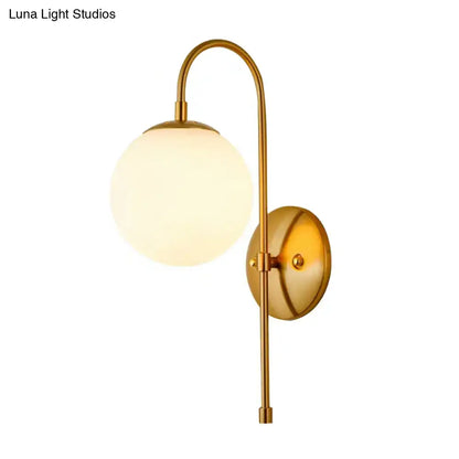 Gold mini globe sconce with frosted glass shade and brass curved arm by Decorbites on Tampa Home & Garden Store