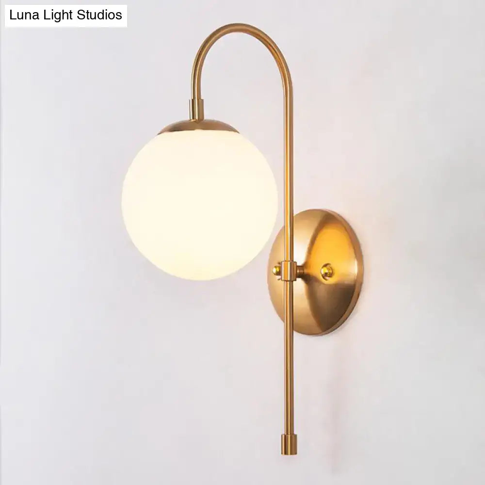 Gold mini globe sconce with frosted glass globe, curved brass arm, round wall plate on Tampa Home & Garden Store