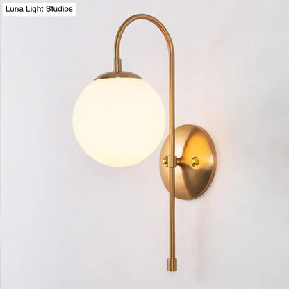 Gold mini globe sconce with frosted glass globe, curved brass arm, round wall plate on Tampa Home & Garden Store
