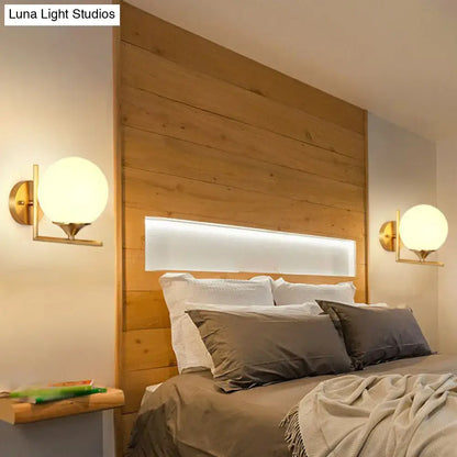 Pair of gold sphere wall sconces by Decorbites with brass finish and frosted glass globes on Tampa Home & Garden Store