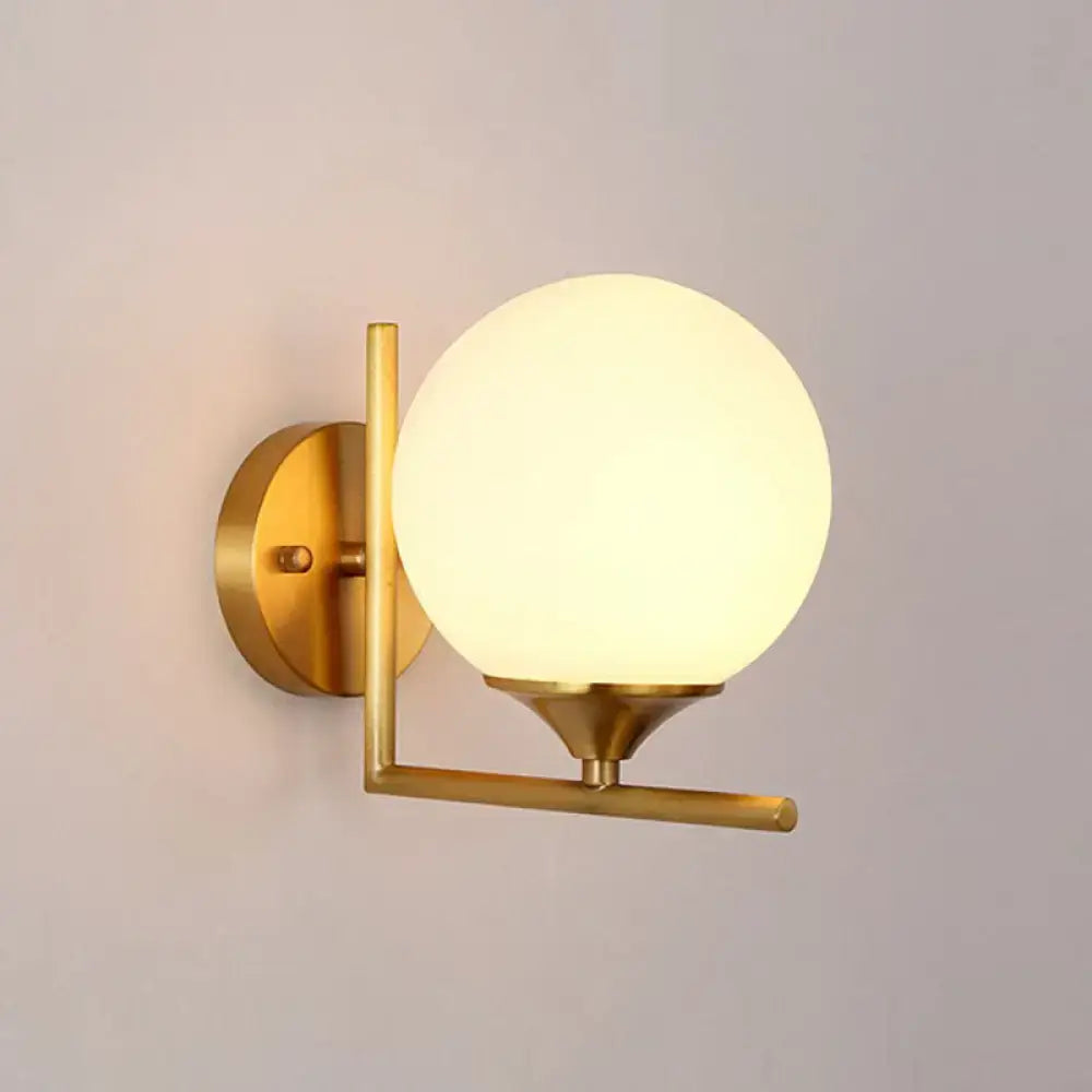 Gold sphere wall sconce with frosted glass globe and brass arm, round backplate on Tampa Home & Garden Store