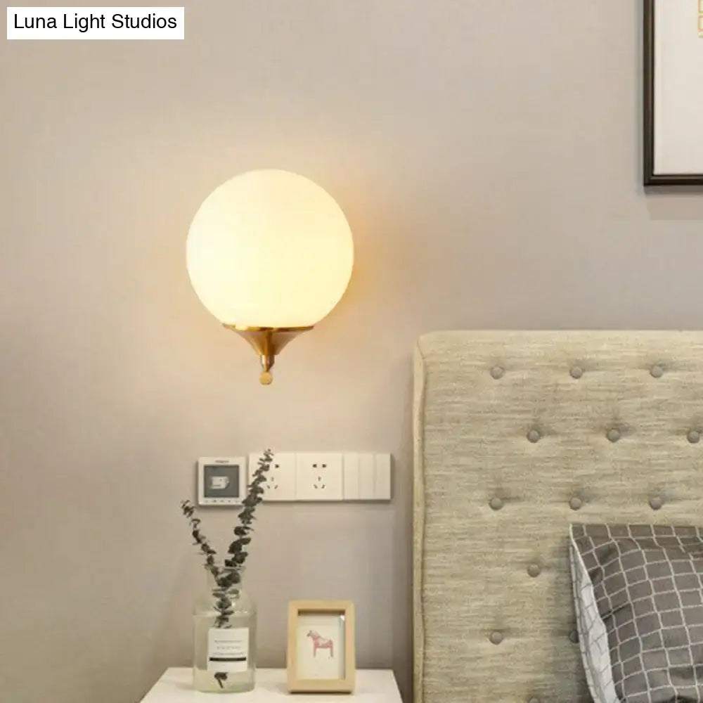Gold sphere wall sconce with brass base and frosted glass globe, warm bedroom lighting on Tampa Home & Garden Store