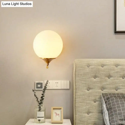 Gold sphere wall sconce with brass base and frosted glass globe, warm bedroom lighting on Tampa Home & Garden Store