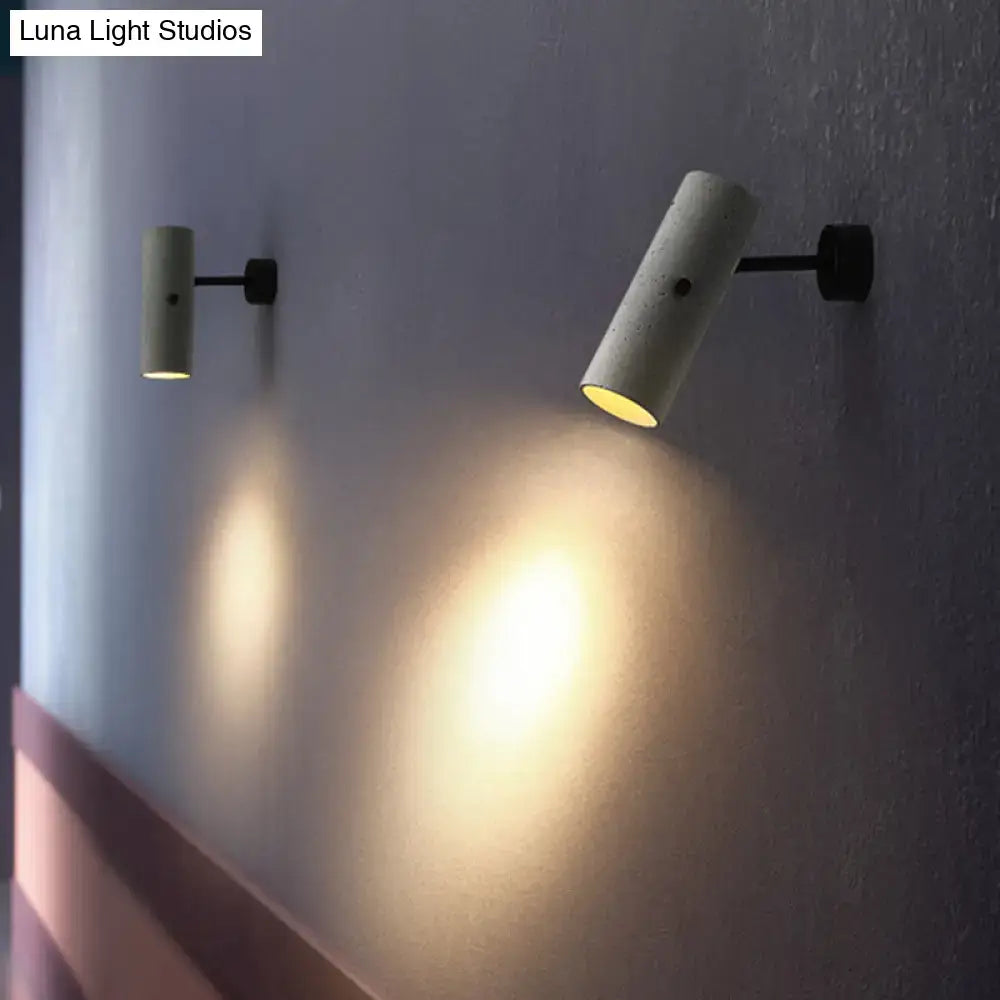 Gray cement wall spotlight pair with cylindrical heads on black mounts casting warm light on Tampa Home & Garden Store