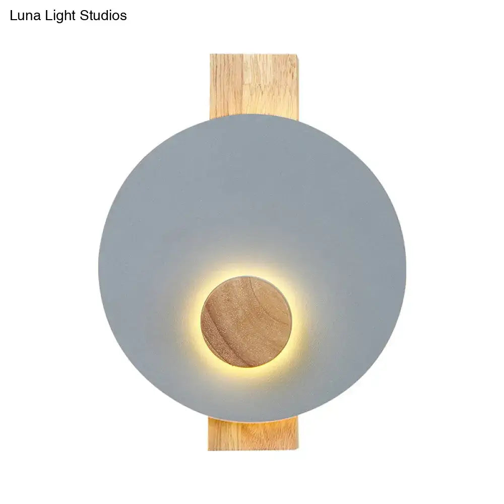 Gray metal disk sconce with wood backplate and warm halo on Tampa Home & Garden Store