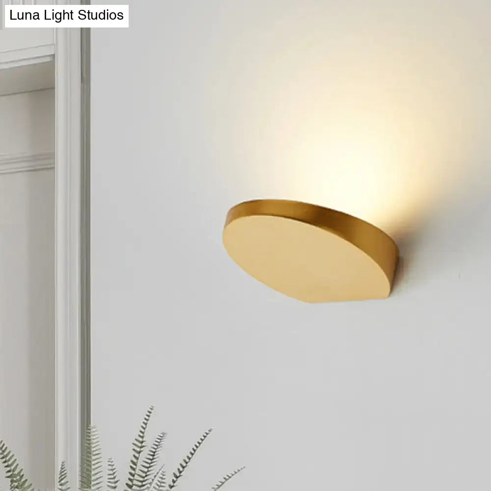 Grey aluminum minimalist corridor sconce, circular brass-tone wall light casting warm glow on wall on Tampa Home & Garden Store