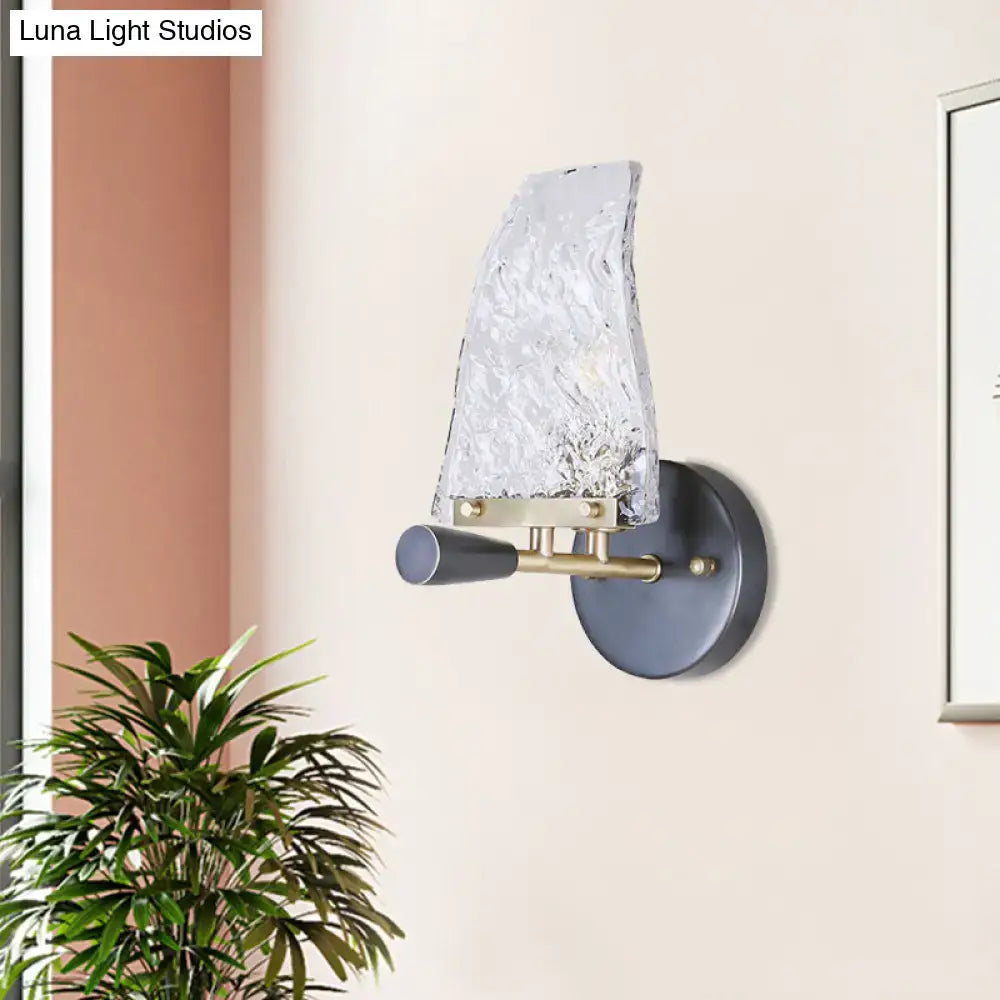 Black brass sail sconce with textured glass sail shade, brass arm, and dark round wall mount on Tampa Home & Garden Store