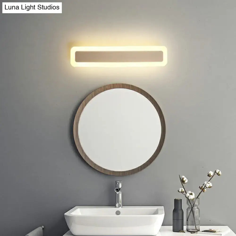 Minimalist white LED vanity light wall sconce above round wood-framed mirror in modern bathroom on Tampa Home & Garden Store