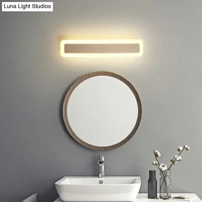 Minimalist white LED vanity light wall sconce above round wood-framed mirror in modern bathroom on Tampa Home & Garden Store