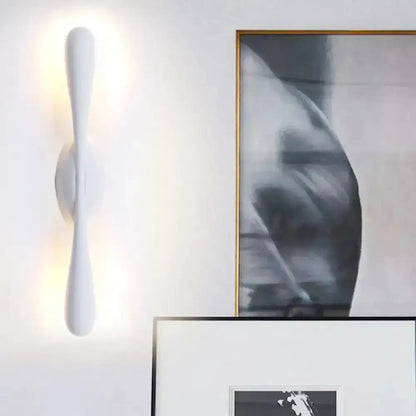 Minimalist white curved wall sconce with vertical form and soft up/down glow on Tampa Home & Garden Store