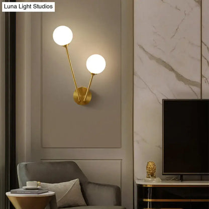 Brass Branch Glass Sconce with dual globe bulbs by Decorbites mounted on a gray wall panel on Tampa Home & Garden Store
