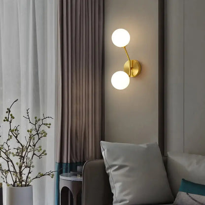 Brass branch glass sconce with two white globe lights by Decorbites mounted on wall on Tampa Home & Garden Store