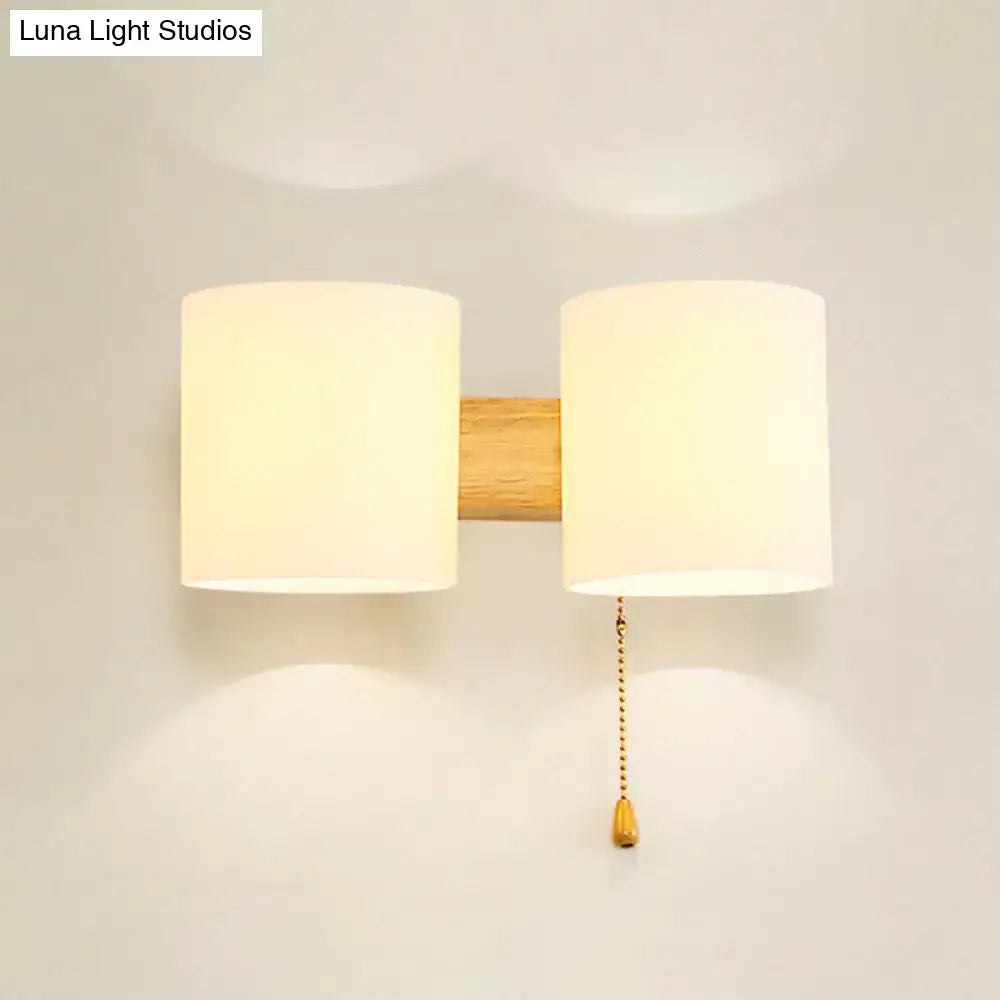 Decorbites beige fabric cylinder wall sconce with dual shades on wood backing and pull chain on Tampa Home & Garden Store
