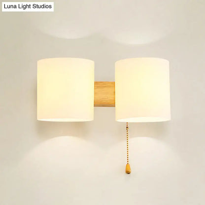 Decorbites beige fabric cylinder wall sconce with dual shades on wood backing and pull chain on Tampa Home & Garden Store