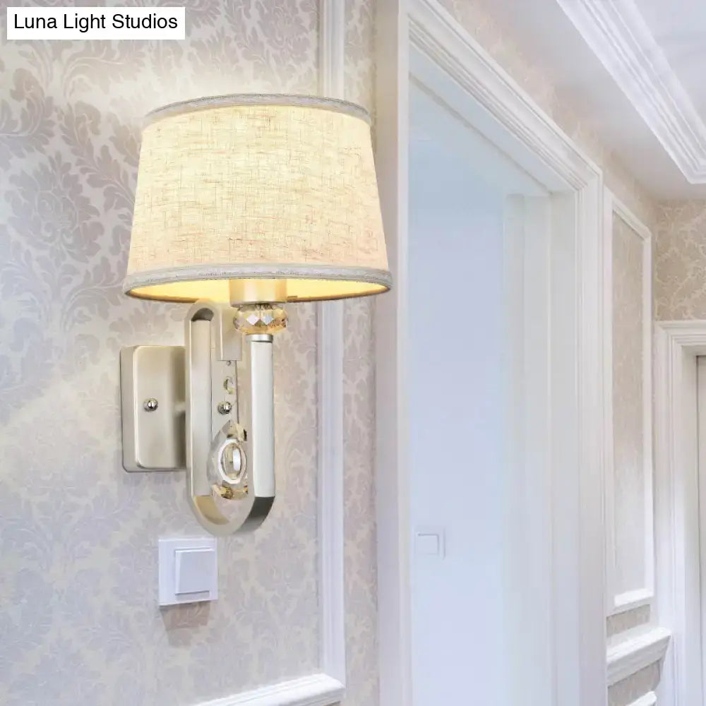 Beige crystal wall sconce with fabric lampshade and crystal accents mounted on wallpapered wall on Tampa Home & Garden Store