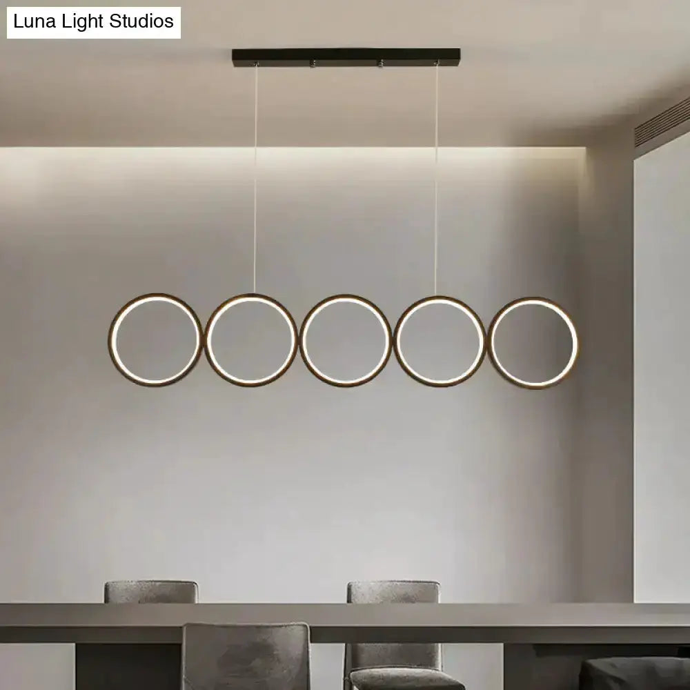 Modern black five-ring LED pendant light with circular rings over dining island on Tampa Home & Garden Store