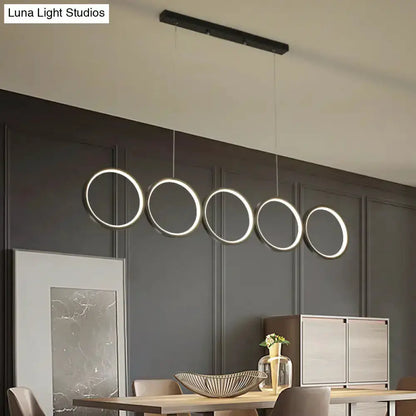 Modern black five-ring LED pendant light over dining island on Tampa Home & Garden Store